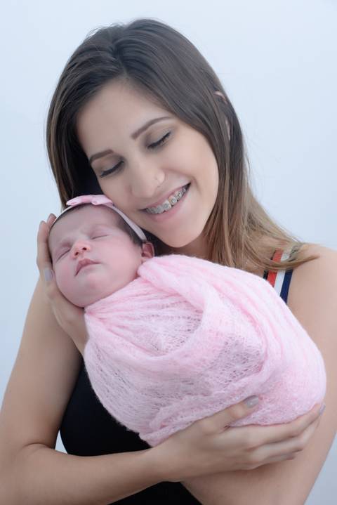 Bebe enrolado no wrap no colo da mae sorrindo, ensaio newborn em casa, fotografa newborn e acompanhamento bebe no tatuape, newborn menina'