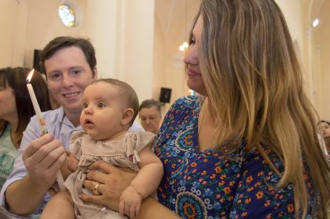 Criança olhando vela com os padrinhos no batizado. Fotografa batizado, cha de bebe, aniversario no tatuape. Foto batismo, igreja são rafael na mooca.'