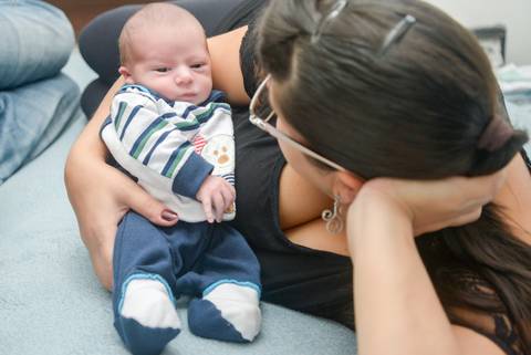 mamae com bebe olhos abertos na cama, ensaio newborn lifestyle, ensaio recem nascido em casa, fotografa newborn no Tatuape'