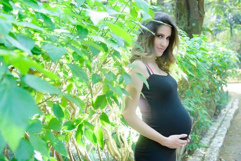 Gestante de vestido preto entre as plantas no parque, ensaio gravida externo, Fotografa gestante tatuape. Fotos iluminaçao de cinema.'