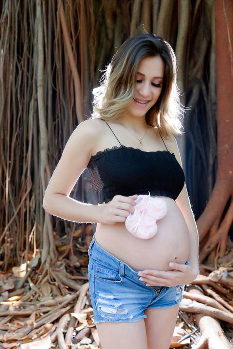 Gestante com sapatinho apoiado na barriga em cenario externo, estilo outono inverno. fotografa ensaio gestante externo, parque piqueri, tatuape.'