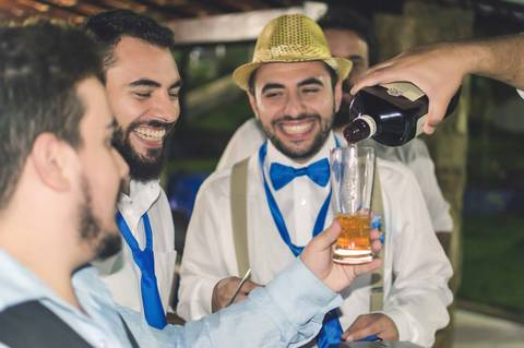 noivo sorrindo no momento da gravata e whisky sendo servido para convidados '