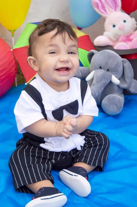 bebe um ano sorrindo em ensaio infantil tema circo vestido de palhaço'