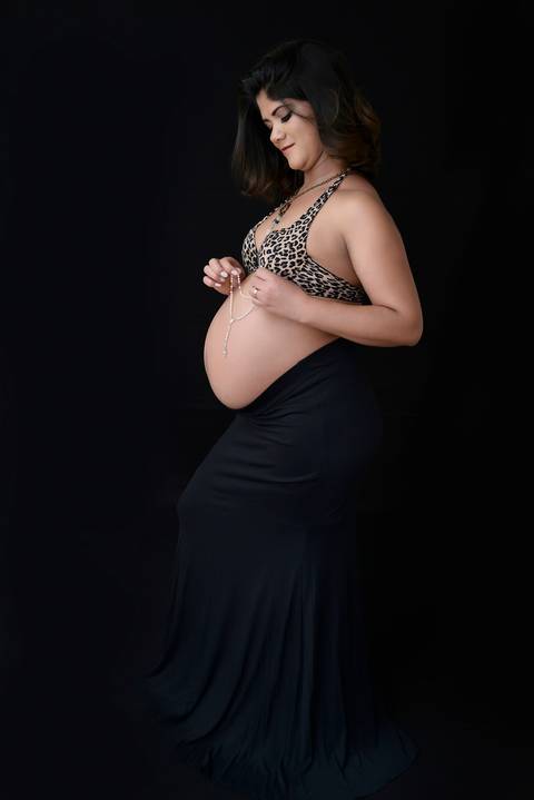 gestante estilo clean em fundo infinito, gestante com terço na mão'