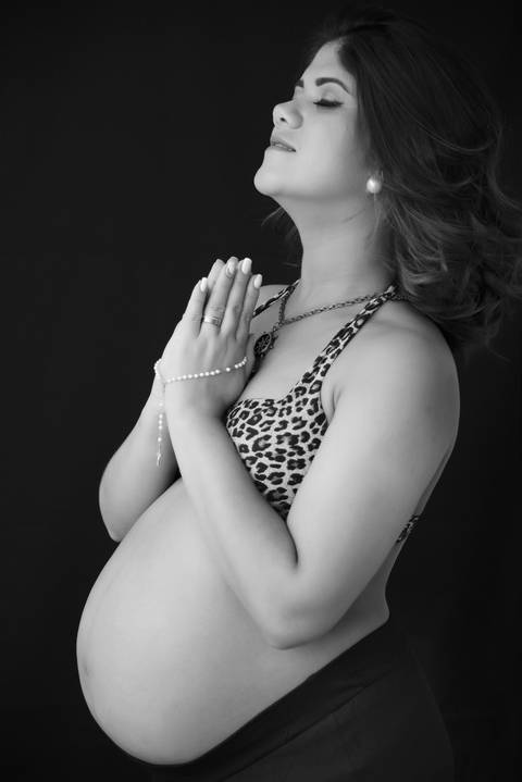 ensaio gestante em preto e branco, gravida com terço na mão agradecendo a vida do bebe'