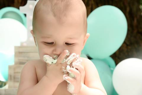 bebe saboreando bolo em ensaio de um ano externo'