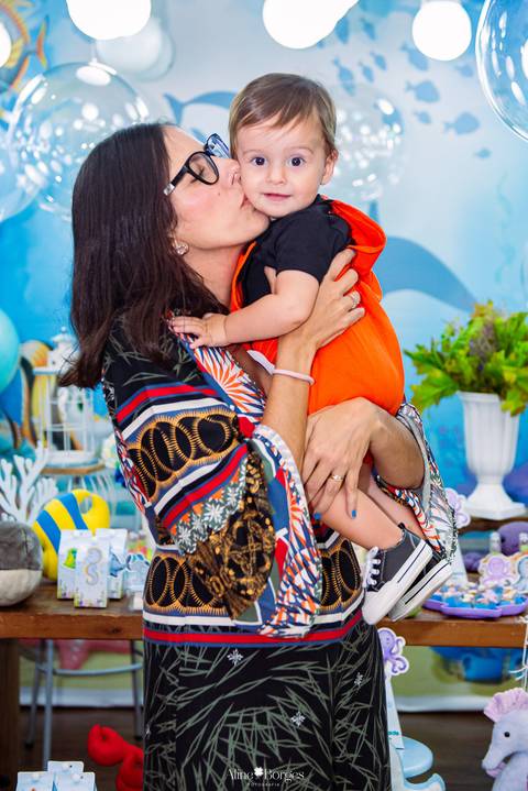 mãe beijando criança em momento de carinho durante festa infantil tema fundo do mar'