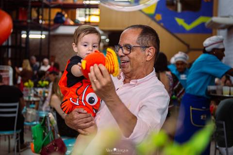 avô interagindo com criança durante aniversário infantil em festa tema fundo do mar'