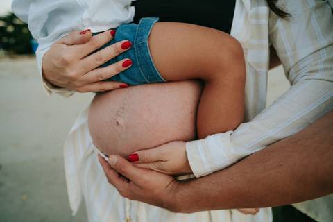 otografia de gestante em Ubatuba destacando a barriga durante ensaio na praia.'