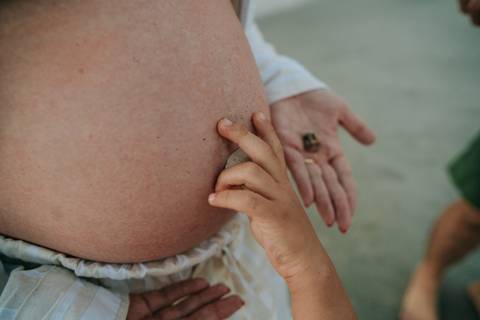 otografia de gestante em Ubatuba destacando a barriga durante ensaio na praia.'