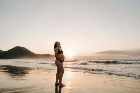 Ensaio gestante na praia em Ubatuba realizado ao pôr do sol.'