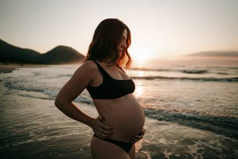 Ensaio gestante na praia em Ubatuba realizado ao pôr do sol.'