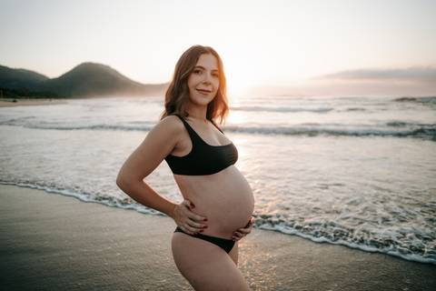 Ensaio gestante na praia em Ubatuba realizado ao pôr do sol.'