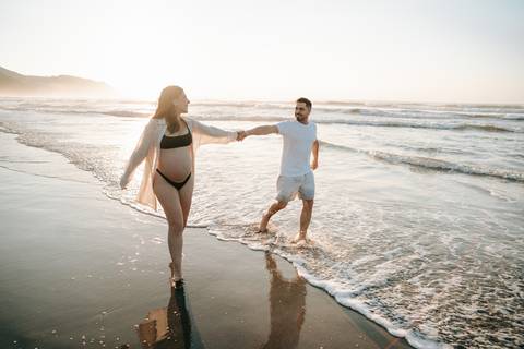 Casal durante ensaio gestante na praia de Ubatuba aguardando a chegada do bebê.'