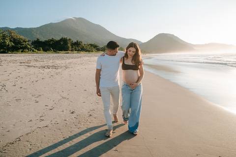 Gestante fotografada na Praia de Itamambuca em Ubatuba durante ensaio gestante ao pôr do sol com luz natural.'
