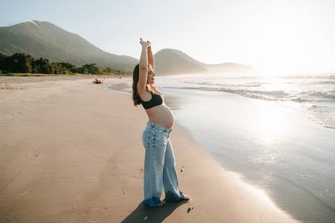 Gestante fotografada na Praia de Itamambuca em Ubatuba durante ensaio gestante ao pôr do sol com luz natural.'