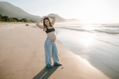 Gestante fotografada na Praia de Itamambuca em Ubatuba durante ensaio gestante ao pôr do sol com luz natural.'