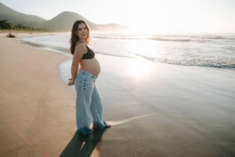 Ensaio gestante na praia em Ubatuba realizado ao pôr do sol.'