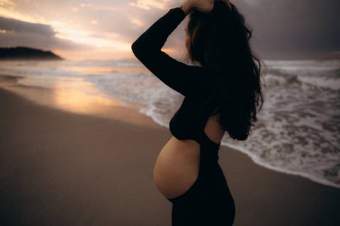 Gestante fotografada na Praia de Itamambuca em Ubatuba durante ensaio gestante ao pôr do sol com luz natural.'