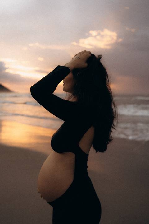 Gestante fotografada na Praia de Itamambuca em Ubatuba durante ensaio gestante ao pôr do sol com luz natural.'