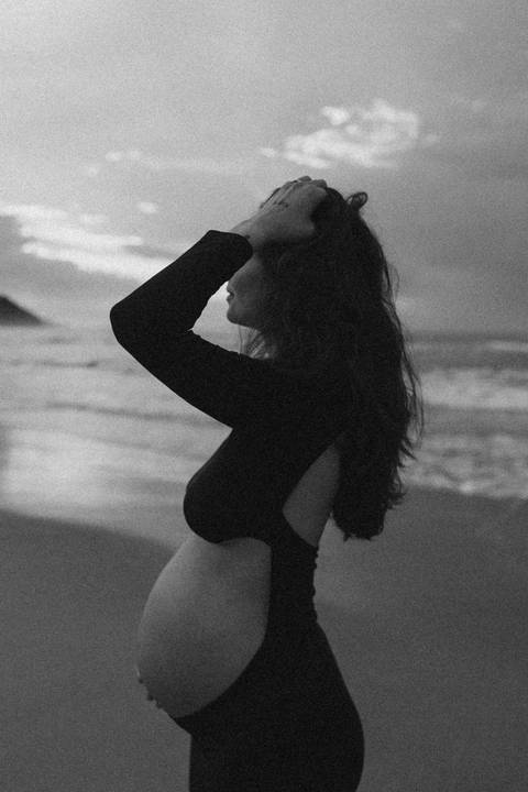Gestante fotografada na Praia de Itamambuca em Ubatuba durante ensaio gestante ao pôr do sol com luz natural.'