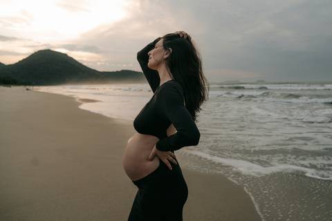 Ensaio gestante na praia em Ubatuba realizado ao pôr do sol.'