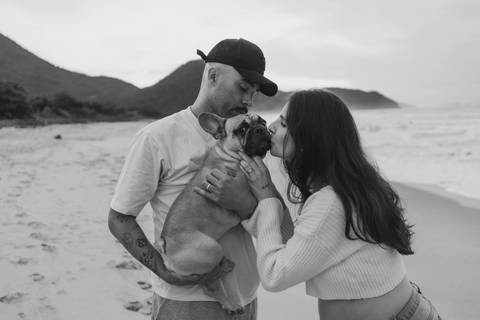 Ensaio gestante na praia com cachorro da família, registrado com luz natural em Ubatuba.'