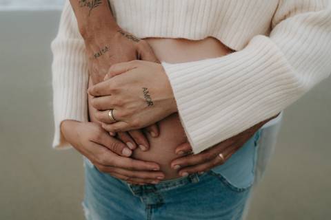 Fotografia de gestante em Ubatuba destacando a barriga durante ensaio na praia.'
