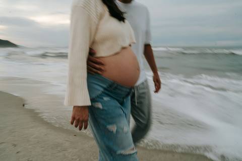 Fotografia de gestante em Ubatuba destacando a barriga durante ensaio na praia.'