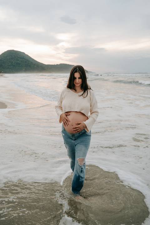Fotografia de gestante em Ubatuba destacando a barriga durante ensaio na praia.'
