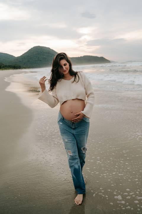 Fotografia de gestante em Ubatuba destacando a barriga durante ensaio na praia.'