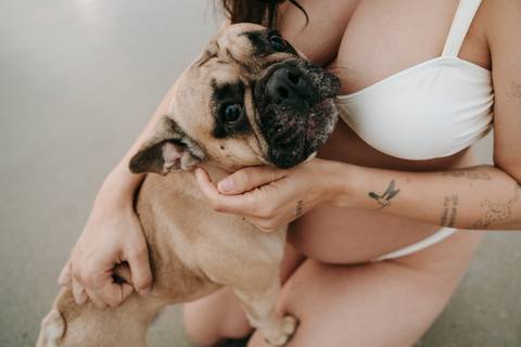 Gestante acariciando seu cachorro durante ensaio fotográfico na Praia de Itamambuca em Ubatuba.'