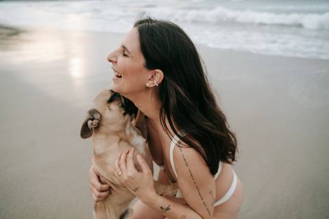 Mulher grávida abraçando seu cachorro durante ensaio gestante ao ar livre em Ubatuba.'
