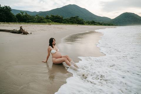 Gestante fotografada na Praia de Itamambuca em Ubatuba durante ensaio gestante ao pôr do sol com luz natural.'