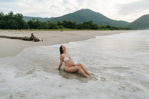 Gestante fotografada na Praia de Itamambuca em Ubatuba durante ensaio gestante ao pôr do sol com luz natural.'