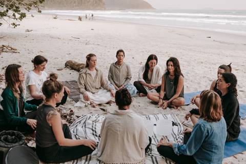 Grupo praticando Yoga ao ar livre durante retiro em Ubatuba'