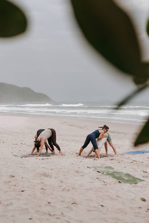 Grupo praticando Yoga ao ar livre durante retiro em Ubatuba'