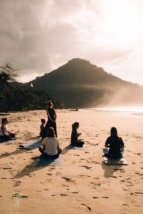 Grupo praticando Yoga ao ar livre durante retiro em Ubatuba'