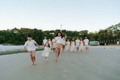 Família caminhando pela areia durante ensaio fotográfico na Praia do Tenório'