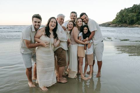 Família caminhando pela areia durante ensaio fotográfico na Praia do Tenório'
