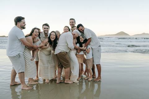 Família caminhando pela areia durante ensaio fotográfico na Praia do Tenório'