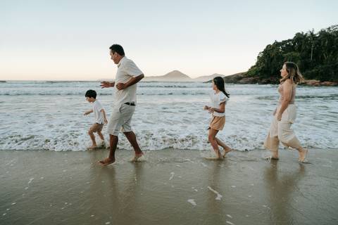 Família entrando no mar durante ensaio fotográfico em Ubatuba'