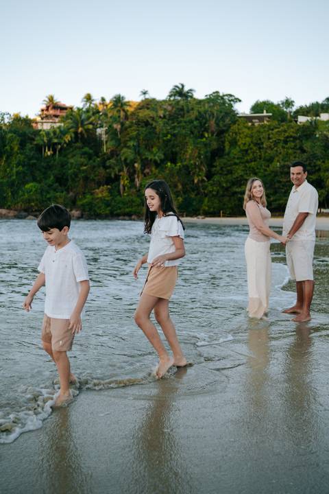 Irmãos brincando juntos durante ensaio família na praia de Ubatuba'