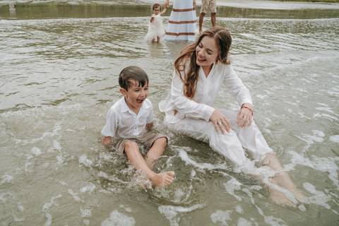 Família entrando no mar durante ensaio fotográfico em Ubatuba'