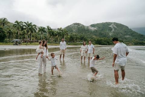 Família entrando no mar durante ensaio fotográfico em Ubatuba'