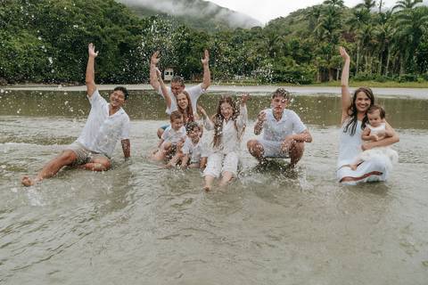 Família entrando no mar durante ensaio fotográfico em Ubatuba'