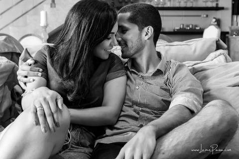 homem e mulher quase se beijando sentados no sofa da sala do loft de macamirim'