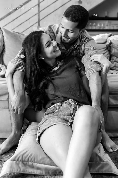 homem sentado no sofá e mulher no chão da sala do loft de macamirim'