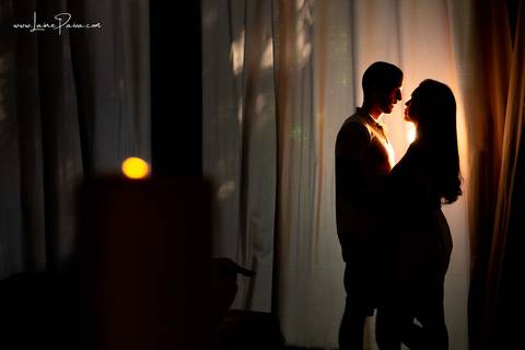 casal abraçado e se olhando com luz atrás dele e vela acesa na frente em sala do loft de macamirim'