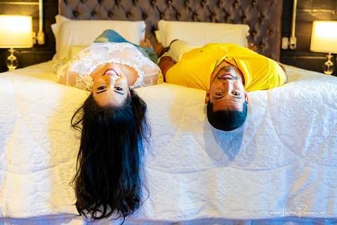 casal deitado na cama com cabeça pra baixo e rindo no quarto do loft de macamirim'